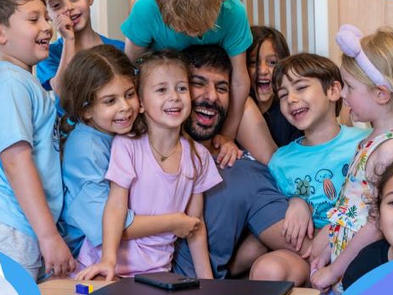 أطفال يضحكون حول مدرّبهم في مخيم La Folie في HandPrint، أم سقيم، دبي